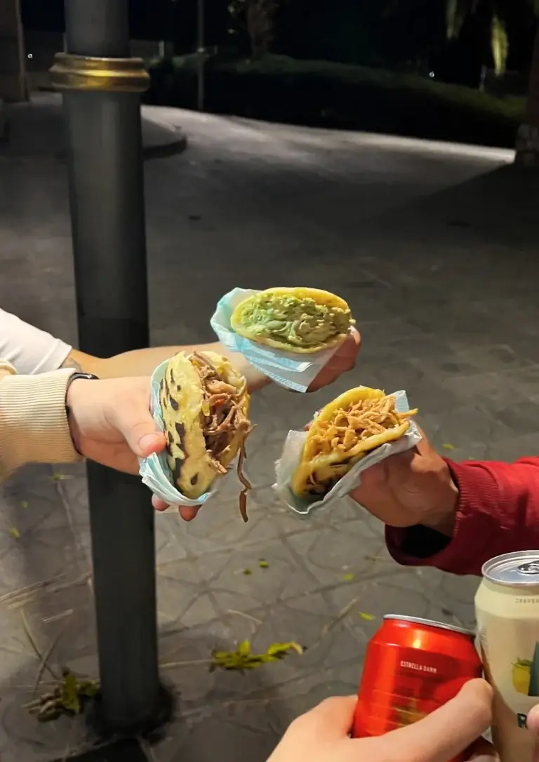 Amigos compartiendo una comida de Estrella Sabanera. Comiendo cada uno una Arepa con relleno distontos como Reina Pepiada, de Pollo o Carne Mechada.