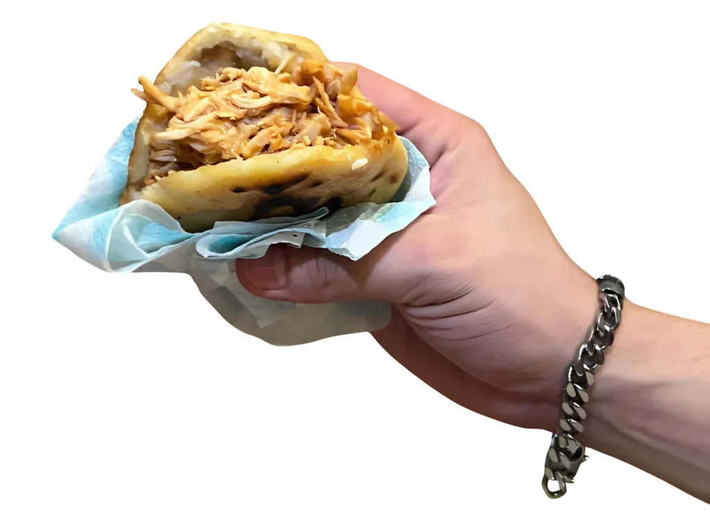 Mano con una Arepa Naguara, rellena de pollo. Comida con sazón.